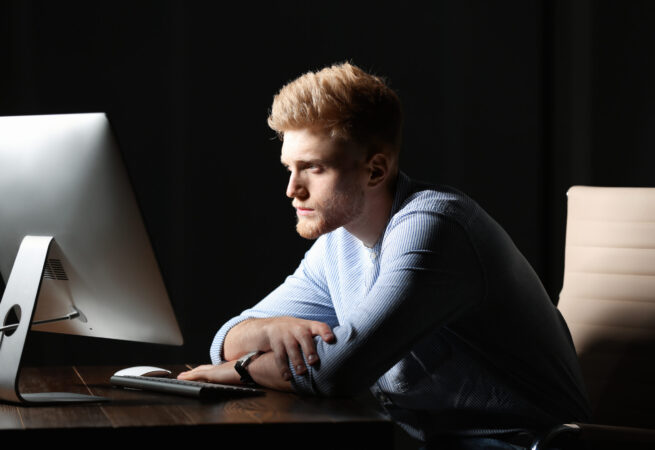 Tired young man working in office alone at night